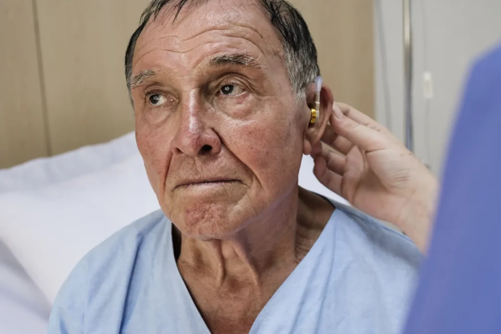 médico audiólogo colocando audífonos a adulto mayor