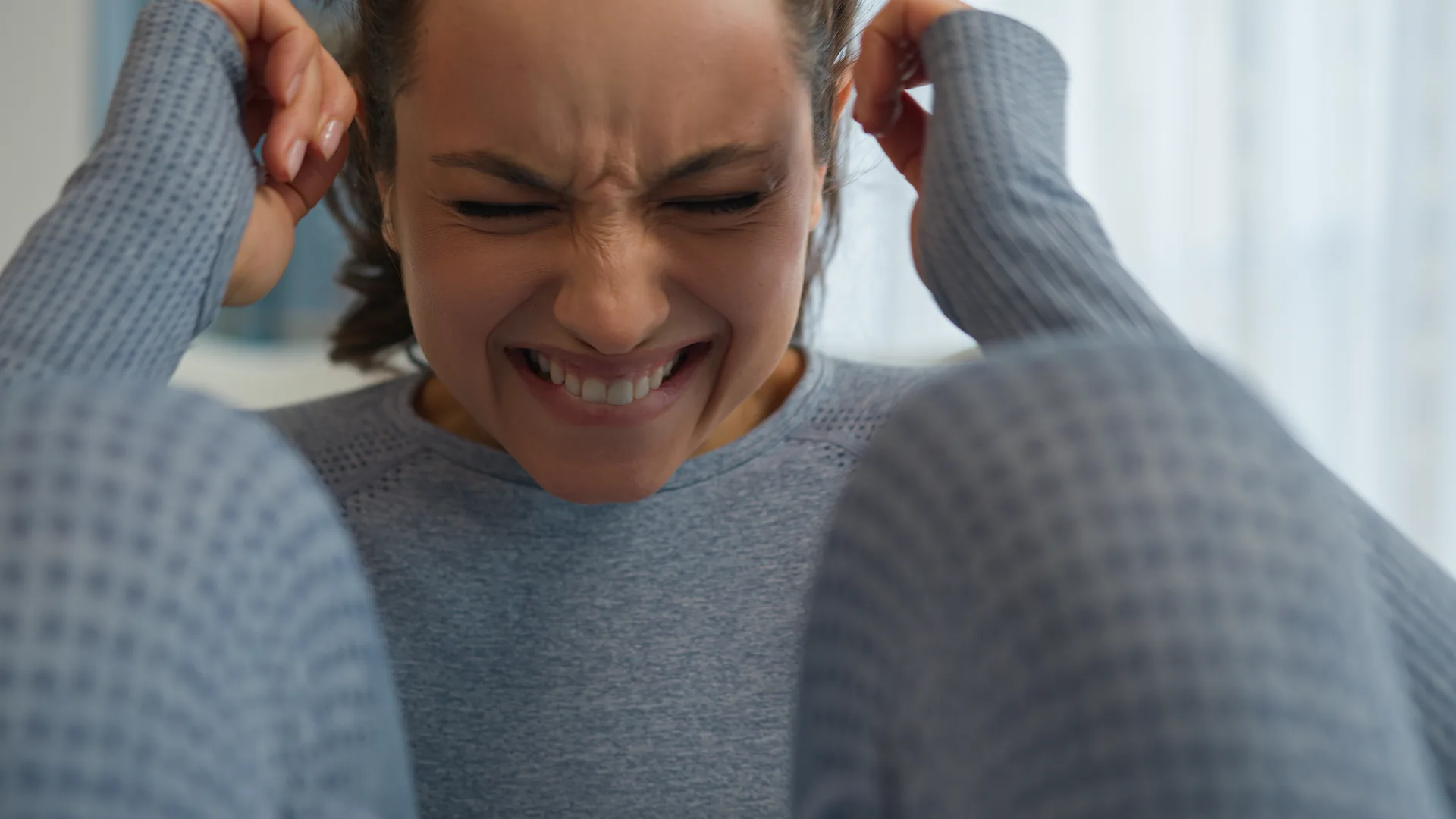 cómo proteger los oídos del ruido: mujer con gesto de molestia por sonido intenso