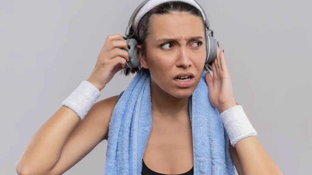 Mujer con sensación de oído taponado tras el entrenamiento, un síntoma habitual de la otitis del nadador en verano