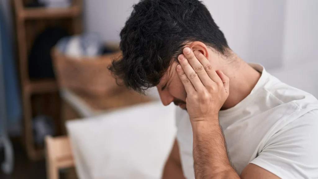 Hombre con molestia cervical, uno de los factores somáticos que se abordan en el tratamiento del tinnitus