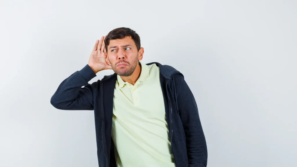 Hombre con síntomas de presbiacusia llevándose la mano a la oreja para escuchar mejor